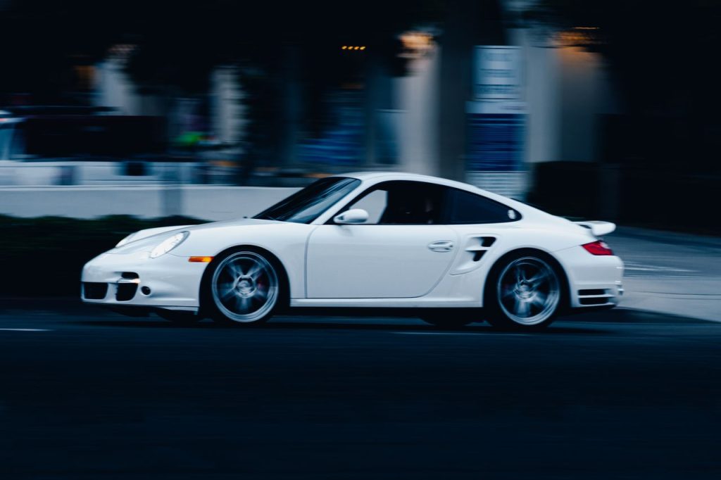 A dynamic shot of a white Porsche in motion on a street in San Diego, capturing speed and elegance.